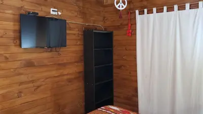 a television hanging on a wall with a curtain and a window at Cabaña Alma in Villa Carlos Paz