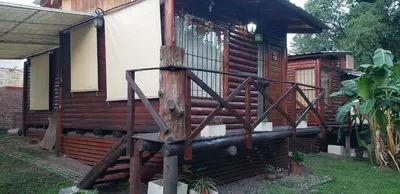 a wooden house with a wooden chair in front of it at Cabaña Alma in Villa Carlos Paz