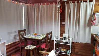 a dining room with a table and chairs and curtains at Cabaña Alma in Villa Carlos Paz