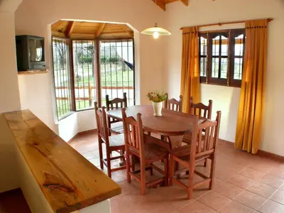 a dining room with a wooden table and chairs at Cabañas Costa Vergel in Los Reartes