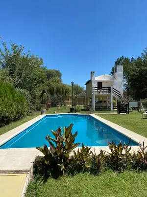 a swimming pool in front of a house at Cabañas Costa Vergel in Los Reartes