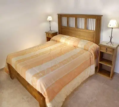 a bedroom with a large bed with two night stands at Cabañas Costa Vergel in Los Reartes