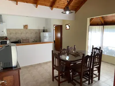 a kitchen and dining room with a table and chairs at Cabañas Costa Vergel in Los Reartes