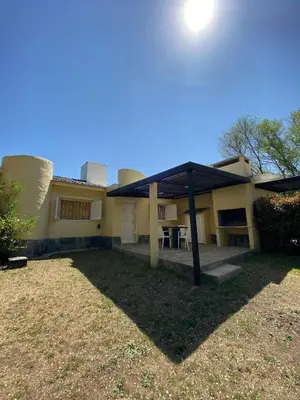 a house with a roof with a table in the yard at Cabañas Costa Vergel in Los Reartes