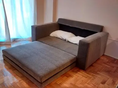 a brown couch with a pillow on a wooden floor at Nueva Córdoba Temporario in Cordoba