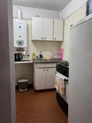 a small kitchen with white cabinets and a refrigerator at Nueva Córdoba Temporario in Cordoba