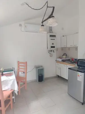 a kitchen with a table and a chair and a stove at La Calma, casa de Rio in Los Reartes