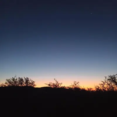 a sunset over a hill with trees in the foreground at Tintitacos in Los Hornillos