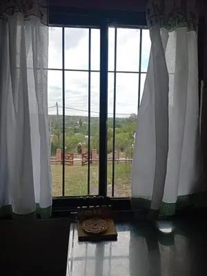 a window with white curtains and a book on the floor at La casita Tanti in Tanti Nuevo