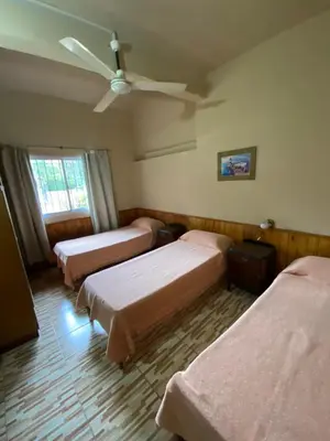 a room with three beds and a ceiling fan at Casa en complejo con pileta compartida in San Roque