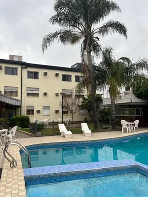 a swimming pool with chairs and a building at Gran Lourdes Hotel in Villa Carlos Paz