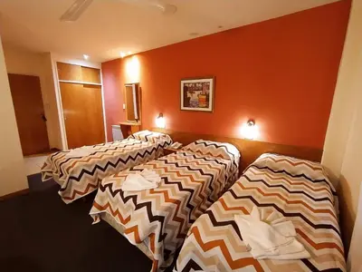 three beds lined up in a room with orange walls at Gran Lourdes Hotel in Villa Carlos Paz