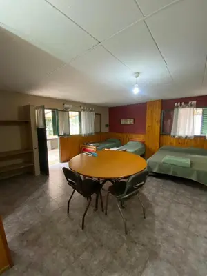 a room with a table and chairs and beds at Departamento con pileta compartida en complejo in San Roque