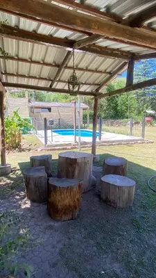 a group of tree stump benches under a pergola at Departamento con pileta compartida en complejo in San Roque