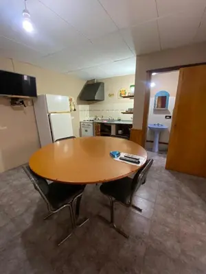 a kitchen with a wooden table and two chairs at Departamento con pileta compartida en complejo in San Roque
