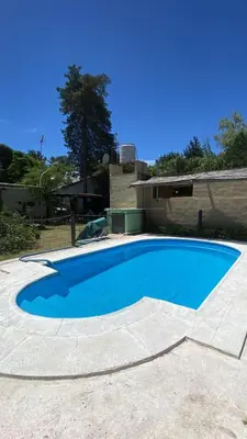 a large blue swimming pool in front of a house at Departamento con pileta compartida en complejo in San Roque