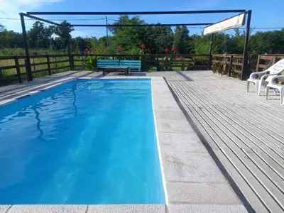 a blue swimming pool with a bench on a deck at CabañaReartes in Los Reartes