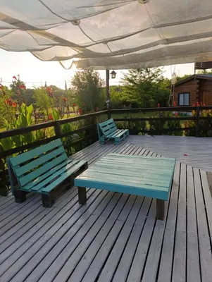 two blue benches sitting on a deck with an umbrella at CabañaReartes in Los Reartes