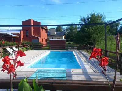 a swimming pool on a wooden deck with red flowers at CabañaReartes in Los Reartes