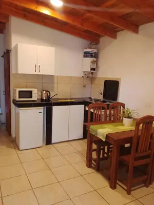 a kitchen with white cabinets and a table with chairs at Depto Calamuchita Rumipal in Villa Rumipal