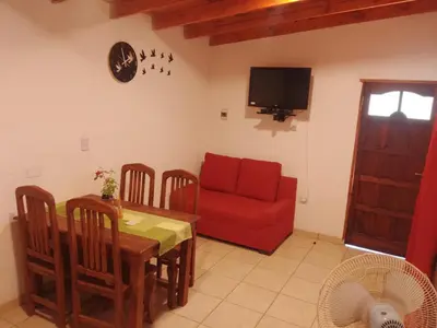 a living room with a table and a red couch at Depto Calamuchita Rumipal in Villa Rumipal