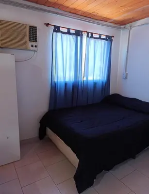a bedroom with a bed and a window with blue curtains at Monoambiente 3 personas in Río Segundo