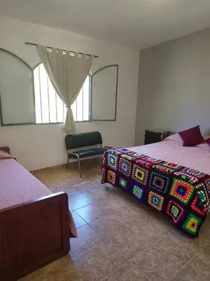 a bedroom with two beds and a chair and window at Casas Los Nogales in Arroyo de Los Patos