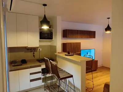 a kitchen with white cabinets and a counter with chairs at Departamento en B Gral Paz, a metros de Hospital Italiano in Cordoba