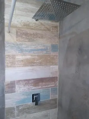 a bathroom with a shower with a wooden wall at Villa Yacanto de Calamuchita in Villa Yacanto