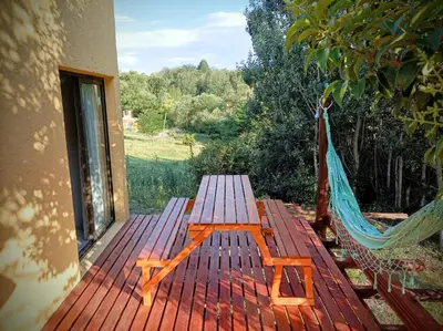 a wooden deck with a hammock on a house at Villa Yacanto de Calamuchita in Villa Yacanto