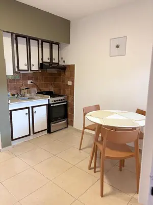 a kitchen with a table and a stove and a table and chairs at Departamento Peatonal de Carlos Paz con Terraza Exclusiva in Villa Carlos Paz
