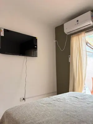 a bedroom with a bed with a television on the wall at Departamento Peatonal de Carlos Paz con Terraza Exclusiva in Villa Carlos Paz