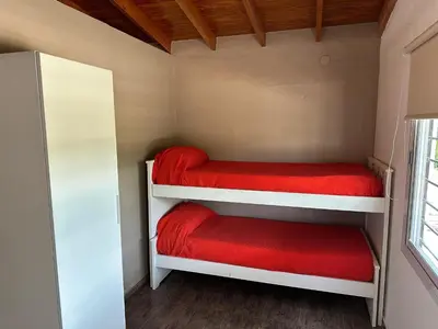 a small room with two bunk beds with red sheets at Loft Cuesta Blanca in Cuesta Blanca