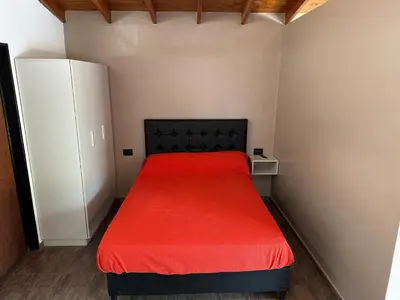 a bedroom with a red bed and a white cabinet at Loft Cuesta Blanca in Cuesta Blanca