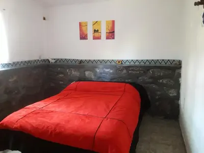 a bed in a room with a red blanket at Cabañas San Gerónimo in San Jerónimo