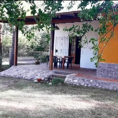 a house with a table and chairs in front of it at Mainumby in Santa Rosa de Calamuchita