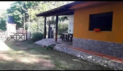 a yellow house with a table and a patio at Mainumby in Santa Rosa de Calamuchita