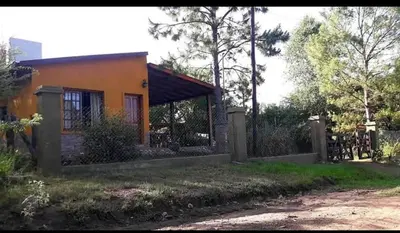 a small orange house with a fence in front of it at Mainumby in Santa Rosa de Calamuchita
