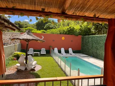 a backyard with a swimming pool with chairs and an umbrella at Verano Paz in Villa Carlos Paz