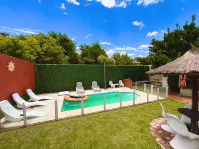 a backyard with a swimming pool with chairs and a table at Verano Paz in Villa Carlos Paz