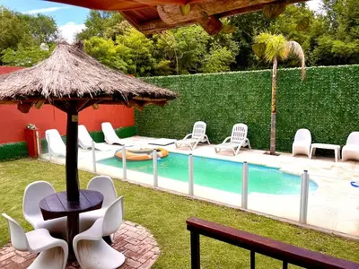 a pool with chairs and a table and a umbrella at Verano Paz in Villa Carlos Paz