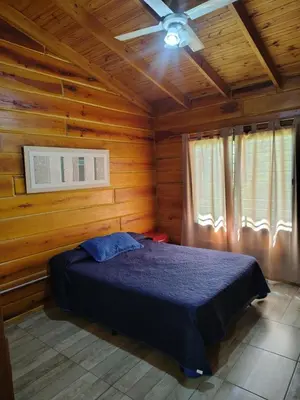 a bedroom with a bed in a wooden cabin at Cabaña Aurora in Santa Rosa de Calamuchita