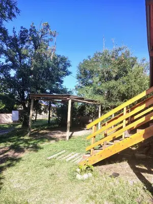 a wooden fence in a field with a wooden shelter at Cabaña Aurora in Santa Rosa de Calamuchita