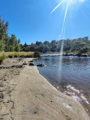 a river with the sun shining on the water at Cabaña Aurora in Santa Rosa de Calamuchita