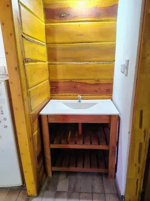 a bathroom with a sink and a wooden wall at Cabaña Aurora in Santa Rosa de Calamuchita