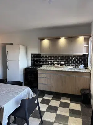 a kitchen with a counter and a refrigerator and a table at Cabañas La Caprichosa in Villa Santa Cruz del Lago