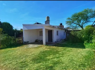 a small white house with a grass yard at Capfer in Alta Gracia