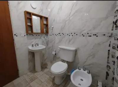 a white bathroom with a toilet and a sink at Capfer in Alta Gracia