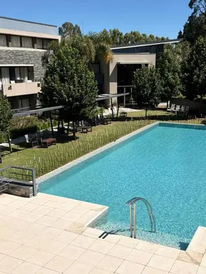 a large swimming pool in front of a building at Altos De Merlo Suites in Merlo