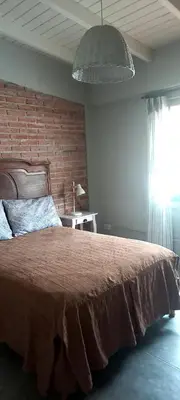 a bedroom with a large bed and a brick wall at La casa de Merlot in San Antonio de Arredondo